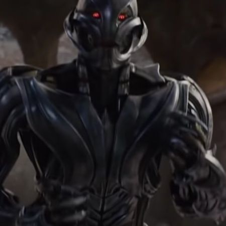 Ultron is looking at someone and has red eyes.